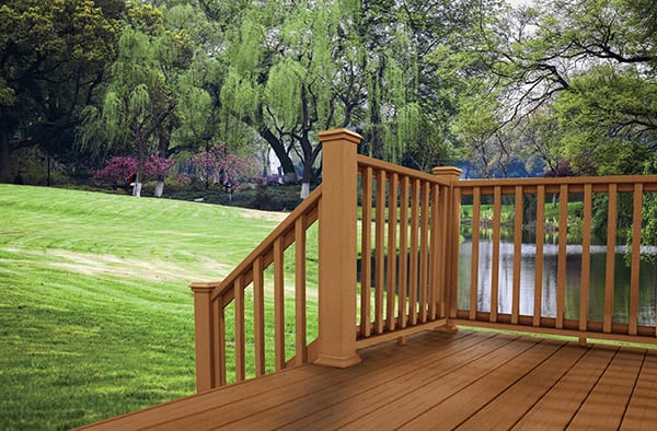 Brown Wooden Deck with a Railing and Steps that Lead to a Large Lush Lawn with a Lake in the Background